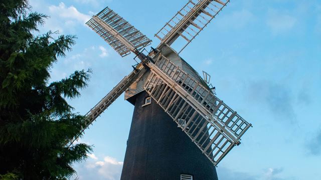 Close up of Shirley Windmill in Croydon with blue sky and tree.