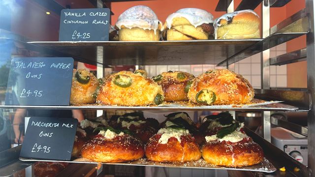 The window of the Chatsworth Bakehouse in Crystal Palace is filled with trays of milk buns with various toppings, ranging from margherita pizza to charred corn.