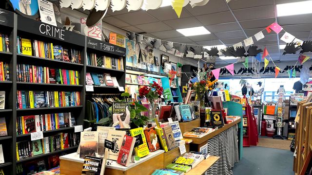 Inside the Crystal Palace bookshop, Bookseller Crow, where books are presented to potential readers by genre, with bunting hanging over.