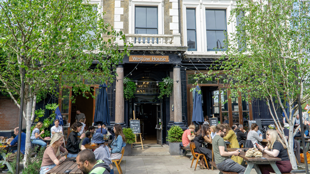Crowds of people sit on picnic tables outside the front on Westow House pub
