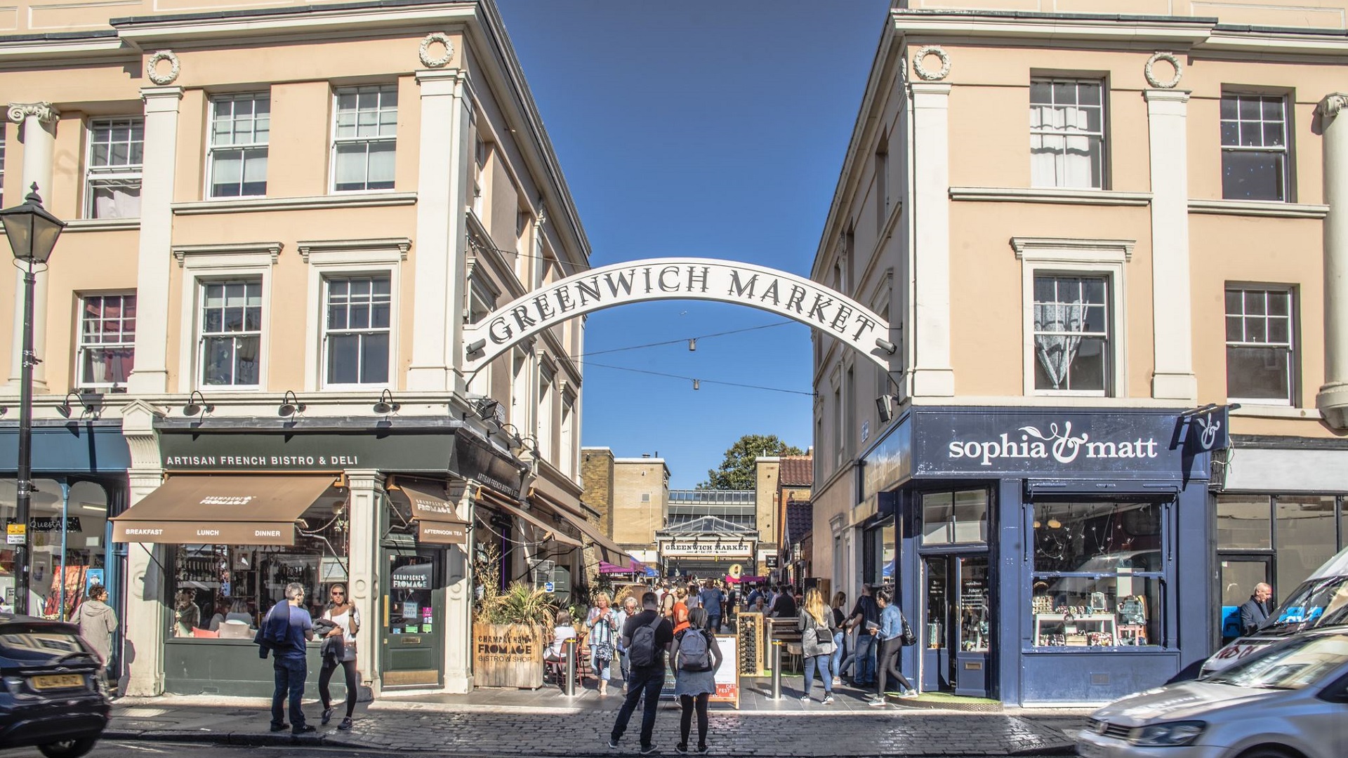 Browse stalls at Greenwich Market. Photo by Ed Simmons. Image courtesy of Greenwich Market. A couple stand in the street looking at the entrance to Greenwich Market.
