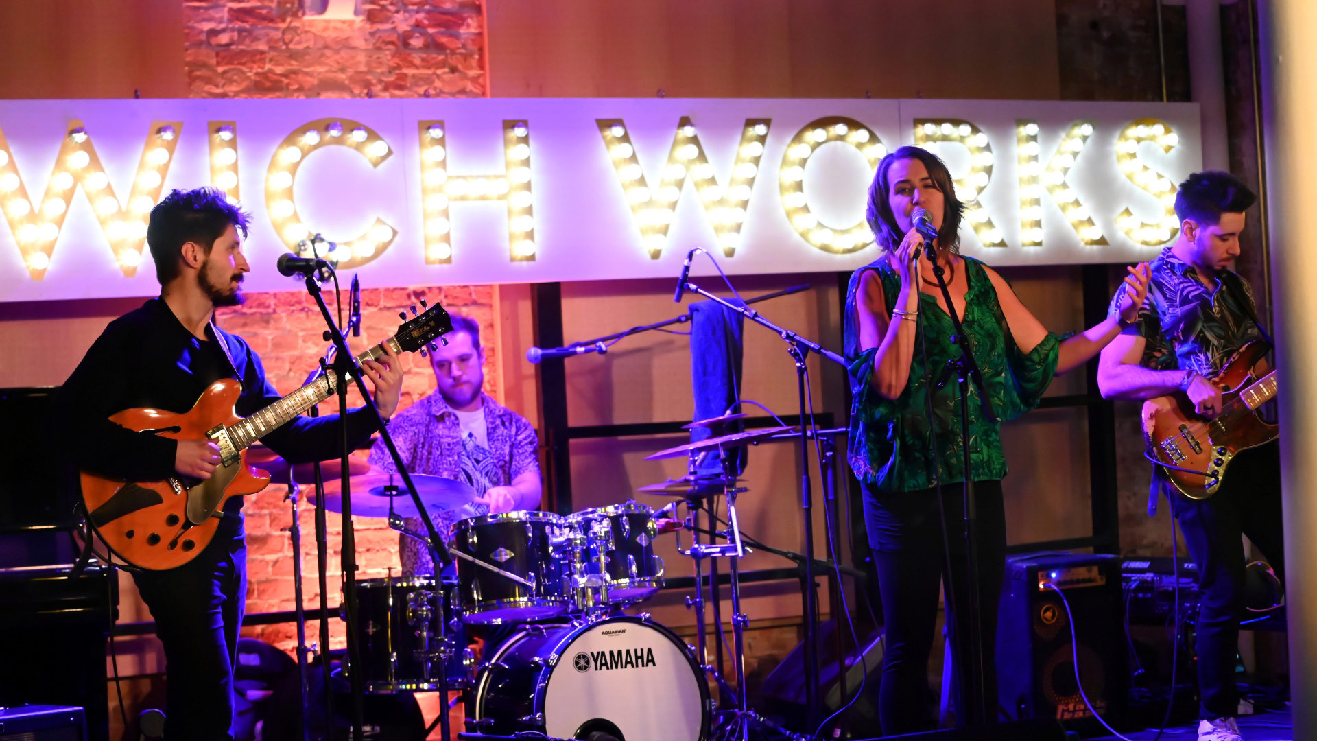 A photo of a singer and band on the stage at Woolwich Works