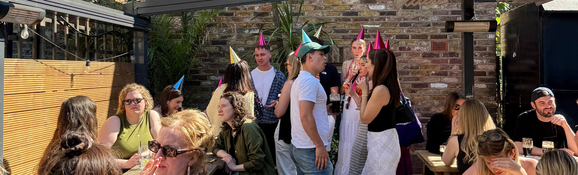 Groups of people sat and stood mingling in the walled garden of Auld Shillelagh in Stoke Newington