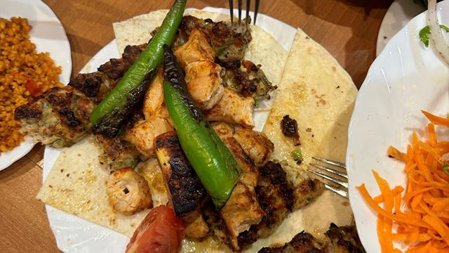 A photo of grilled kebabs, bread, peppers and tomatoes at Mangal 1 Turkish restaurant