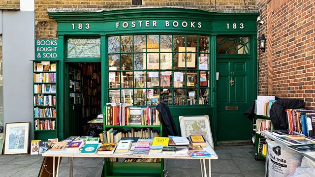 Exterior of Foster Books, a green-fronted bookshop in Chiswick with books displayed outside.