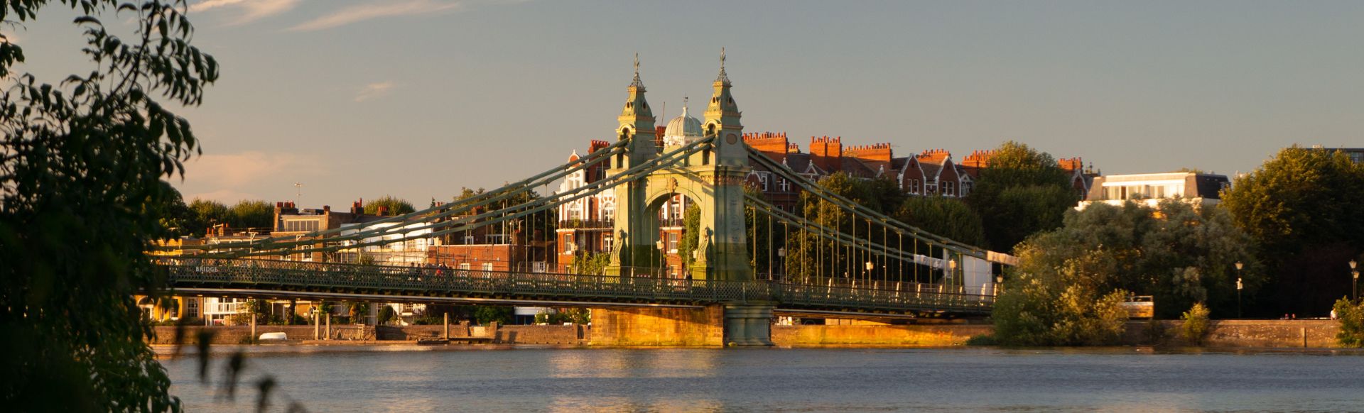 Hammersmith Bridge spanning the river Thames, with Fulham visible beyond.