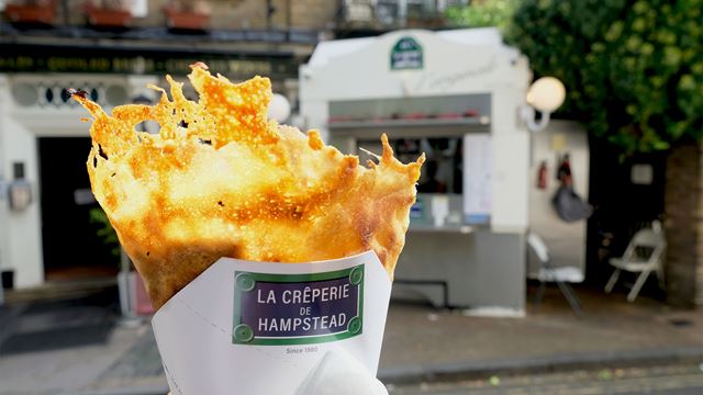 A freshly made crêpe is being held up at La Crêperie de Hampstead, right in front of the stall.