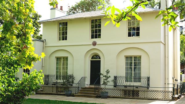 The outside of Keats House in Hampstead, a white villa adorned with a purple plaque above the door indicating the years that John Keats lived there.