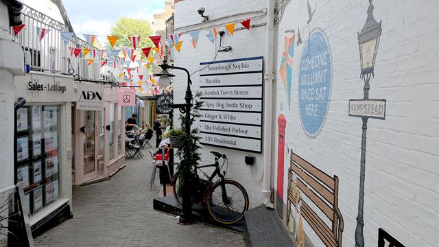 Perrin Court is a tiny alleyway featuring wall art depicting Hampstead, which leads to shops and cafés adorned with colourful bunting that invites curious visitors in.