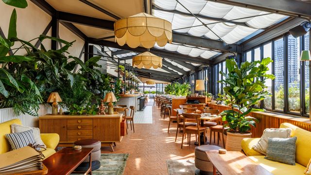 A photo of Llama Inn on the top floor of The Hoxton in Shoreditch with design-led interiors featuring eccentric lamps, yellow sofas and mid-century wooden furniture