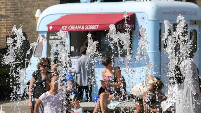 Granary Square fountains with kids playing in the water in summer and blue ice-cream van in the background.