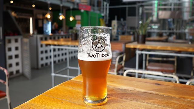A pint of of craft beer on a table inside Two Tribes Brewery's taproom.