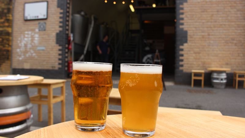 Sample craft beers, local lagers and tasty bites under the railway arches along the Bermondsey Beer Mile. Credit: cktravels.com. Image courtesy of Shutterstock. Two glasses of craft beer on a table outside a taproom on the Bermondsey Beer Mile in south London.