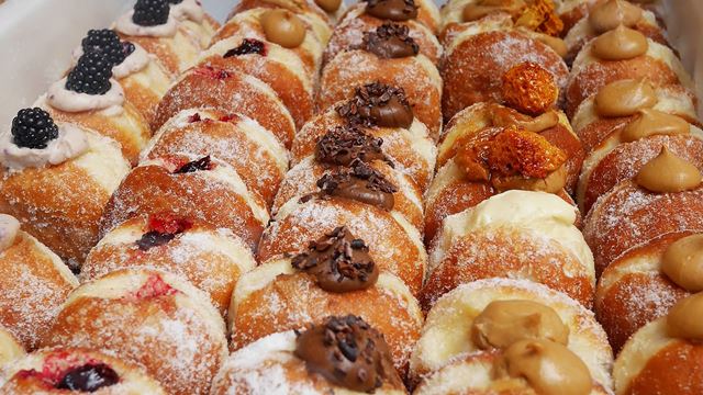 Rows of generously filled doughnuts from Bread Ahead Bakery at Borough Market in London.