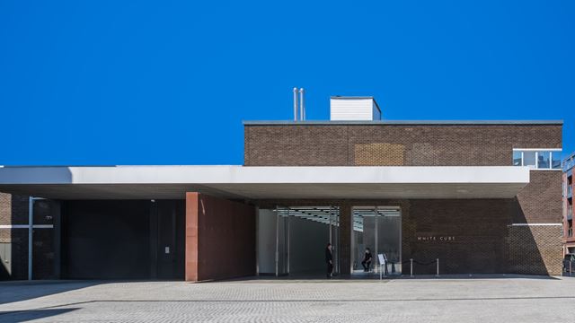Modern brick gallery building with White Cube written next to the entrance and blue sky.