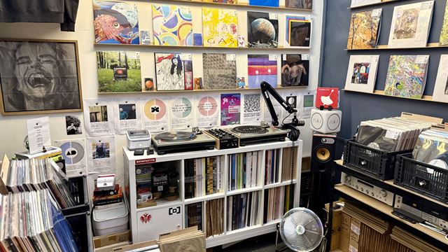 A record store with shelves filled with vinyls and colourful vinyls on the walls.