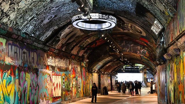 people wandering through graffiti arches, adorned with bright colour paintings and murals by local graffiti artists