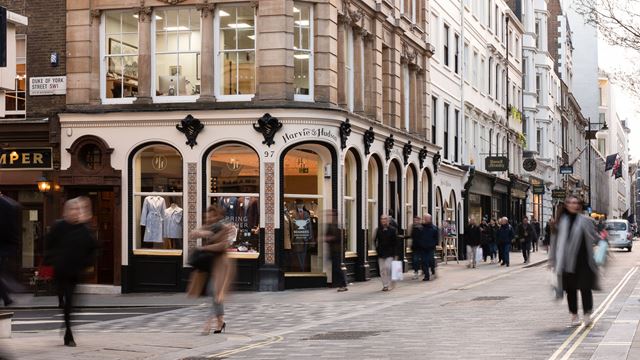A view along Jermyn Street at daytime, showing heritage shops such as Harvie & Hudson, with shoppers walking along the street.