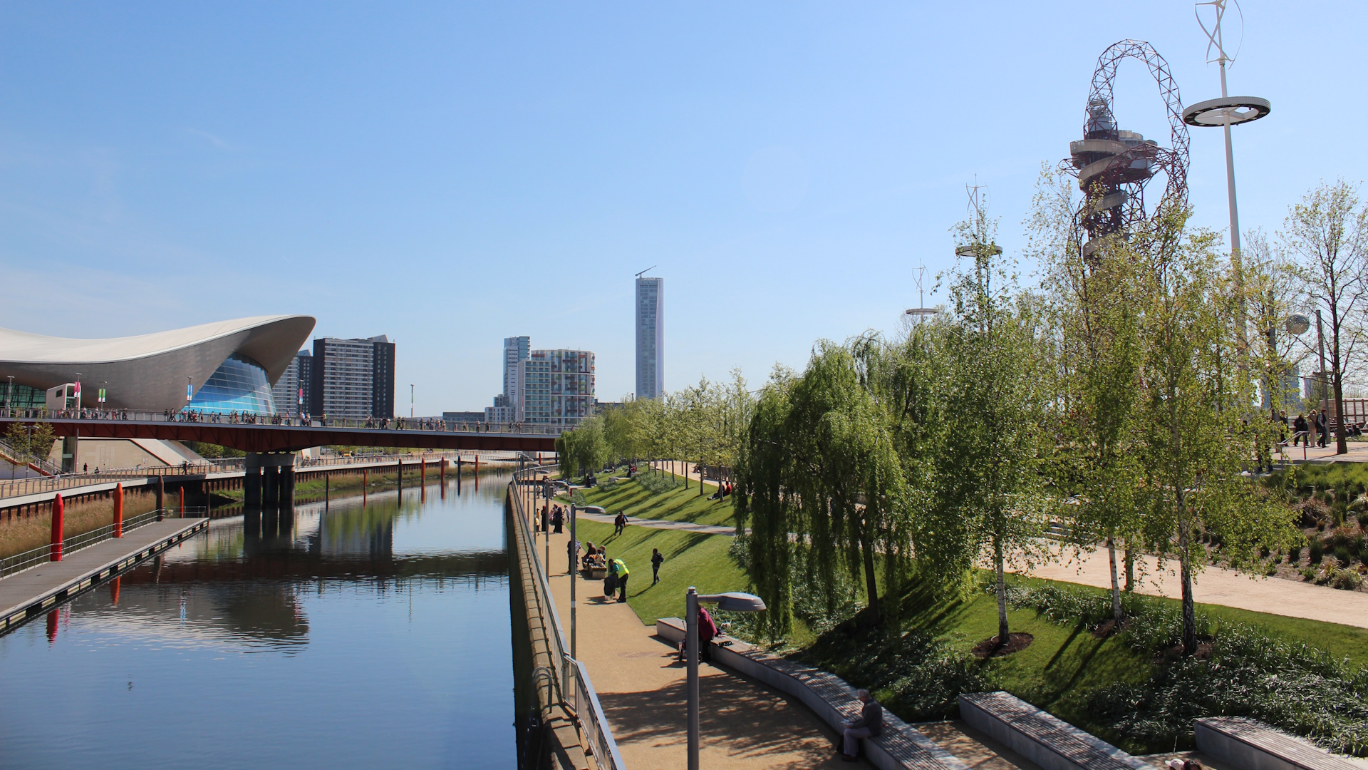 Queen Elizabeth Olympic Park with Aquatics Centre, nature trails, red sculpture and trees on a clear day.