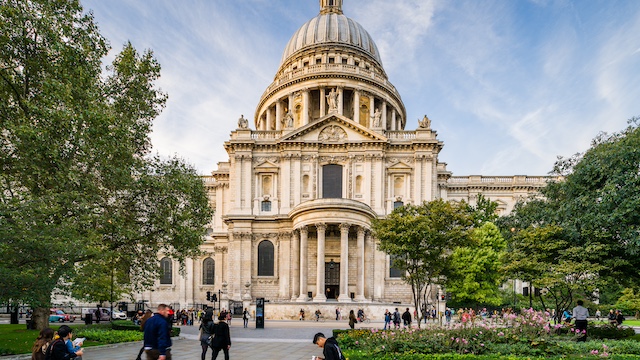 People walking around St Paul's Cathedral in London on a sunny day.