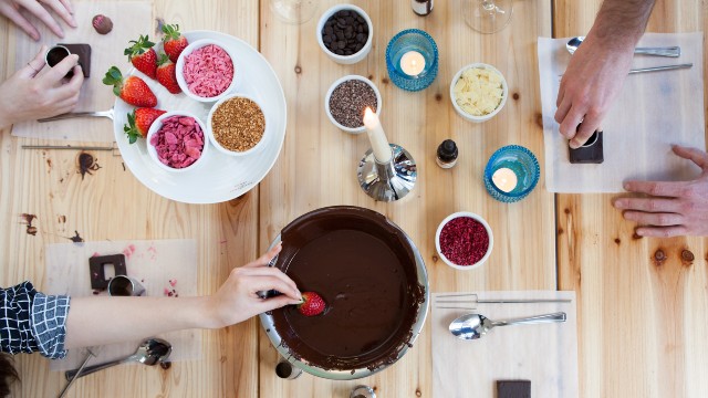 Luxury chocolate-making workshop. Image courtesy of Red Letter Days. Chocolate fondue, strawberries, nuts, seeds, almonds and candles laid out on a wooden table.