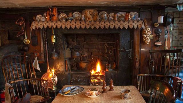 A table with crockery in front of a fireplace at Dennis Severs' House.