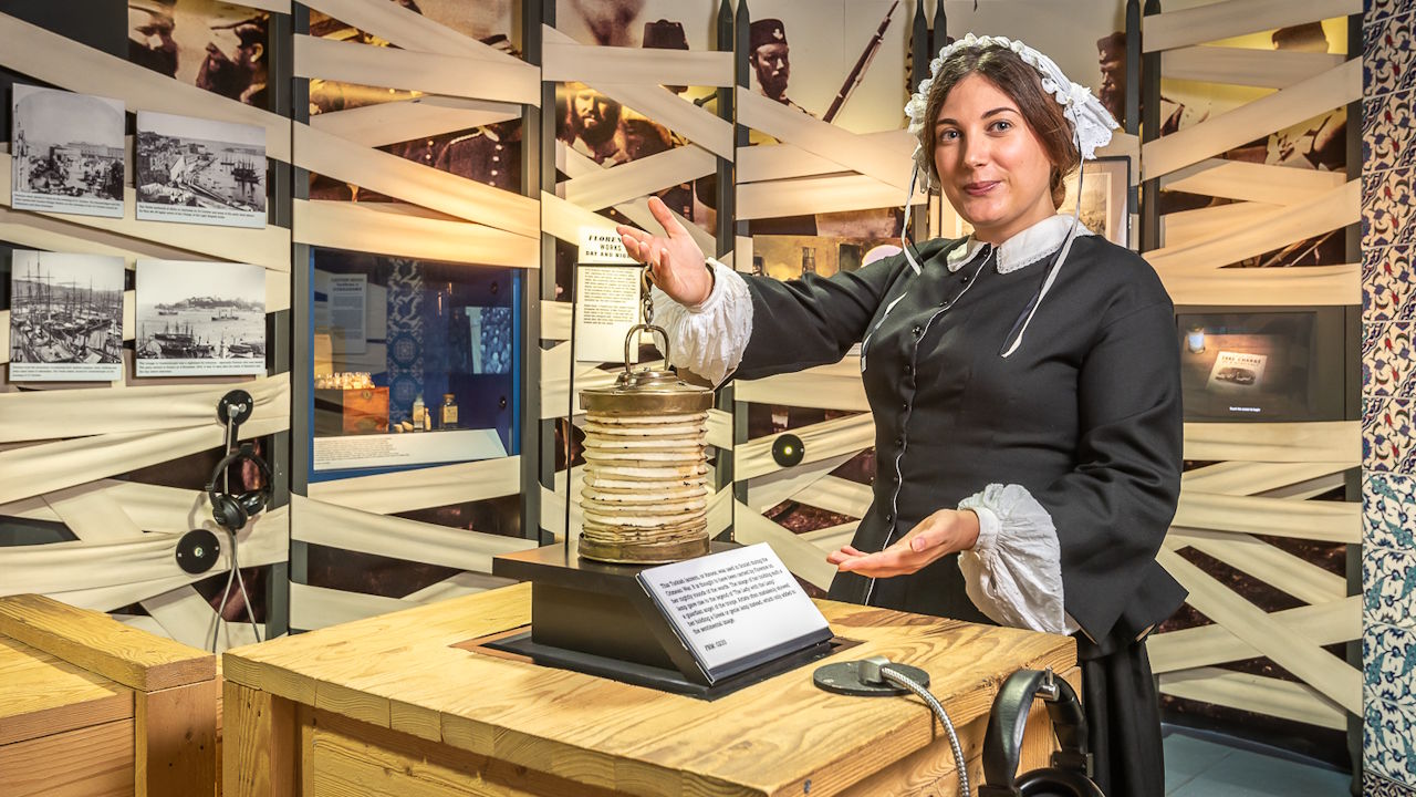 An actor dressed as a nurse, holding the concertina-like fanoos lantern, at the Florence Nightingale Museum.