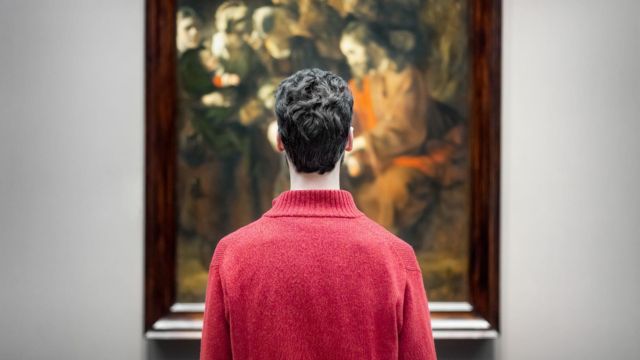 Entdecken Sie außergewöhnliche Werke von weltberühmten Künstlern im National Gallery, London. © National Gallery, London Ein Mann in einem roten T-Shirt steht vor einem Gemälde in der National Gallery in London