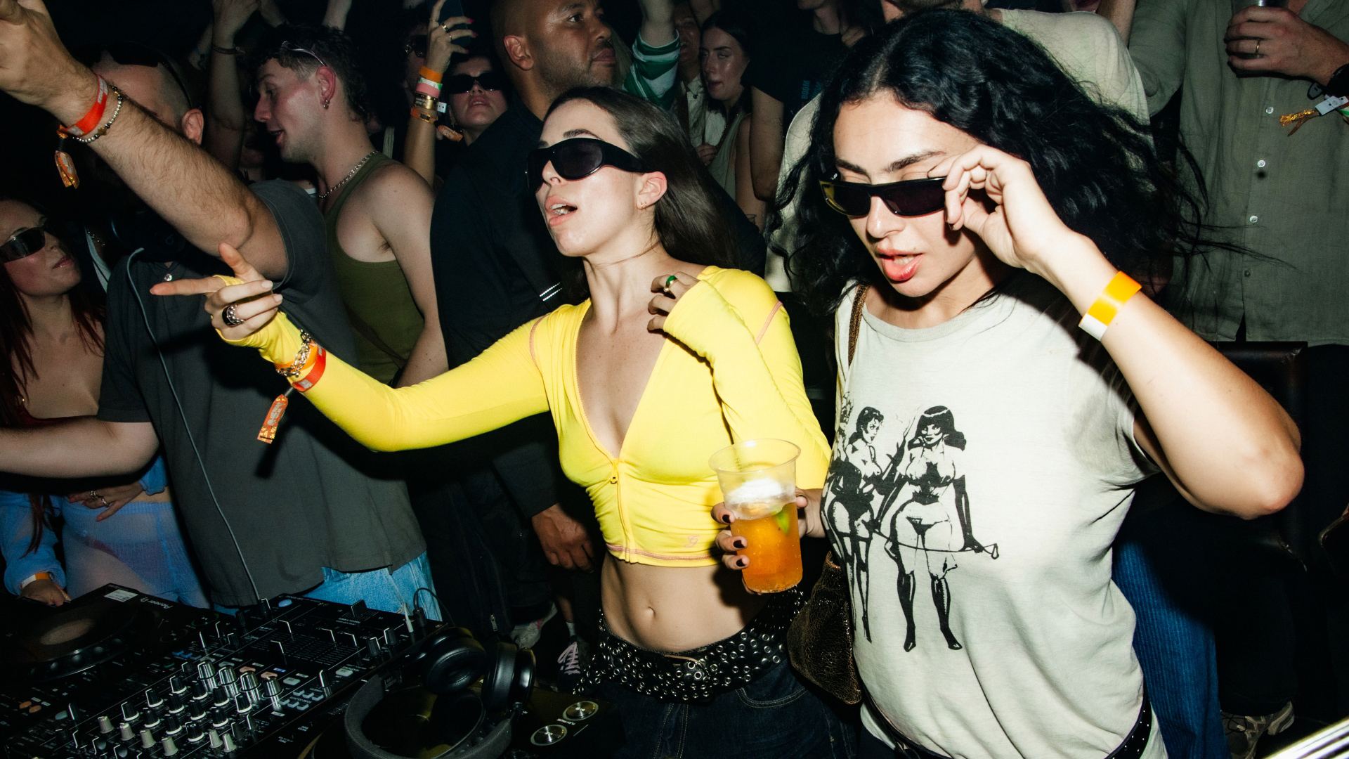 A photo of Charli XCX holding a beer while playing on decks among the crowd at Colour Factory