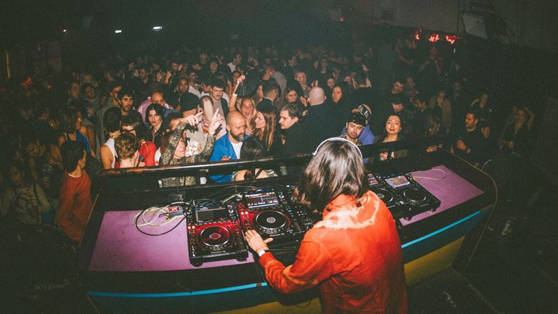 A photo of a DJ playing on decks in front of a crowd at Colour Factory