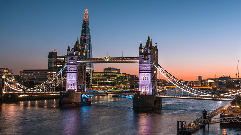 A shot of Tower Bridge lit up at night with The Shard in the background