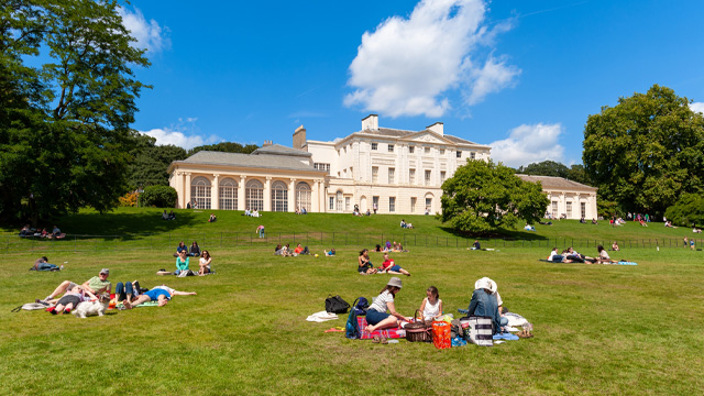 Picnickers sit on the grass outside Kenwood House on Hampstead Heath on a sunny day. 