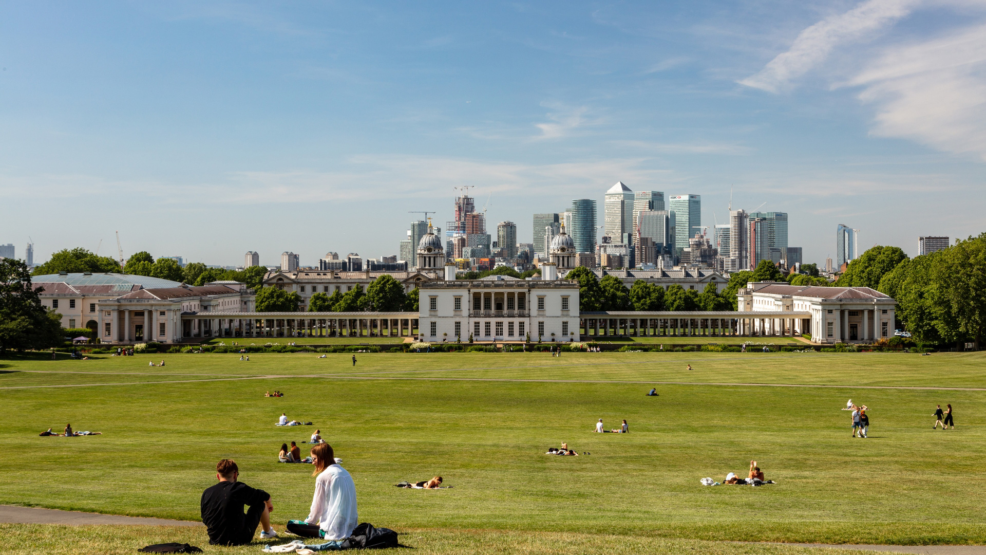 Take in one of the best London views from Greenwich Park. Credit: London & Partners/Jon Reid. Groups of people sit on the hill of Greenwich Park overlooking the Old Royal Naval College and the London skyline.
