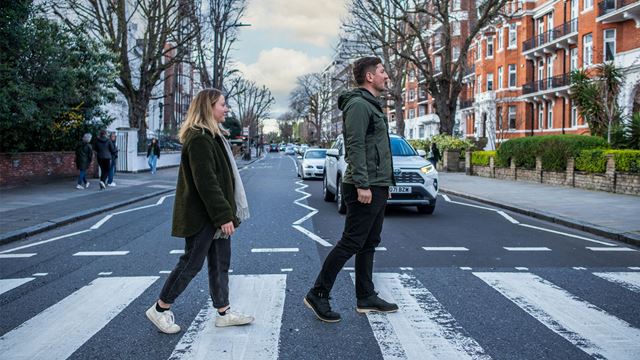 Two people walking across the famous Beatles zebra crossing.