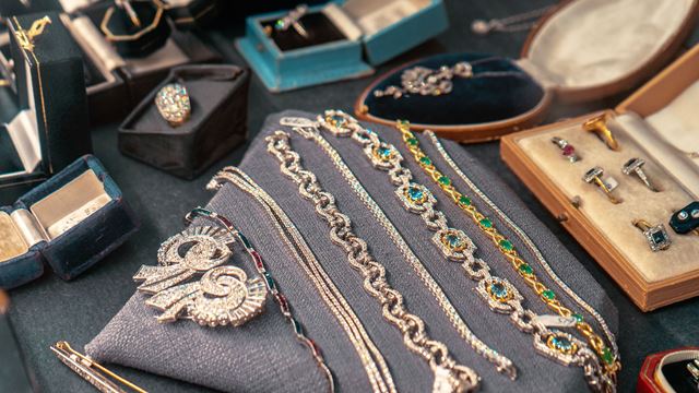 A mixed selection of jewellery being displayed in boxes and on display cushions.