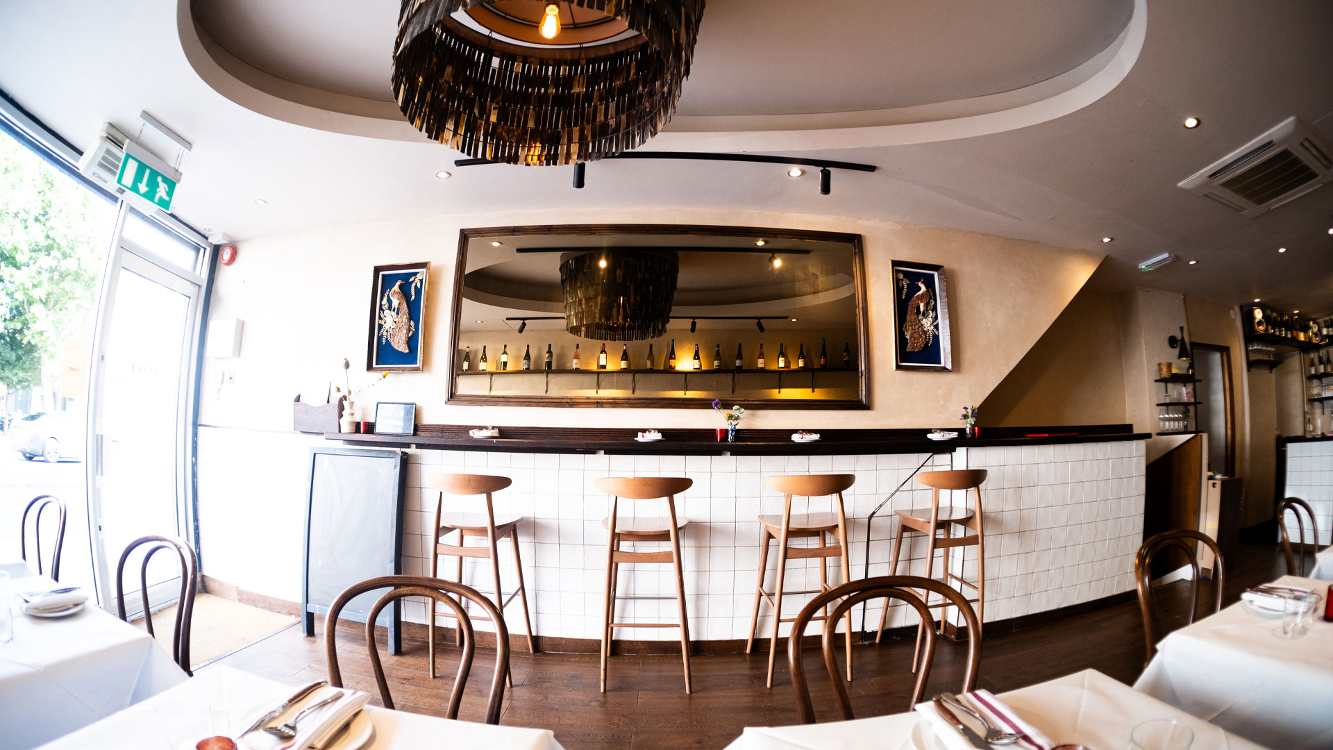 Table and counter seating in the minimalist white interior of Belly Bistro taken with a fish eye lens.