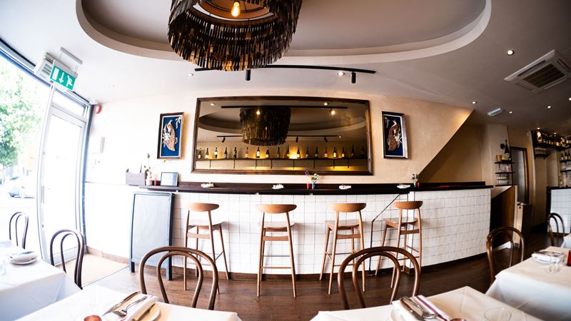 Table and counter seating at Belly Bistro. Credit: Belly Bistro. Image courtesy of Amy Williams Consultancy. Table and counter seating in the minimalist white interior of Belly Bistro taken with a fish eye lens.