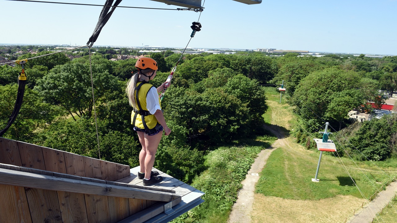 Erleben Sie den ultimativen Adrenalinkick und den freien Fall von einem 24 Meter hohen Turm, der an einem Power Fan-Rückhaltesystem befestigt ist. Bild mit Genehmigung von Golden Tours. Ein Mädchen steht auf der Kante eines 24 Meter hohen Turms und blickt über London hinweg.