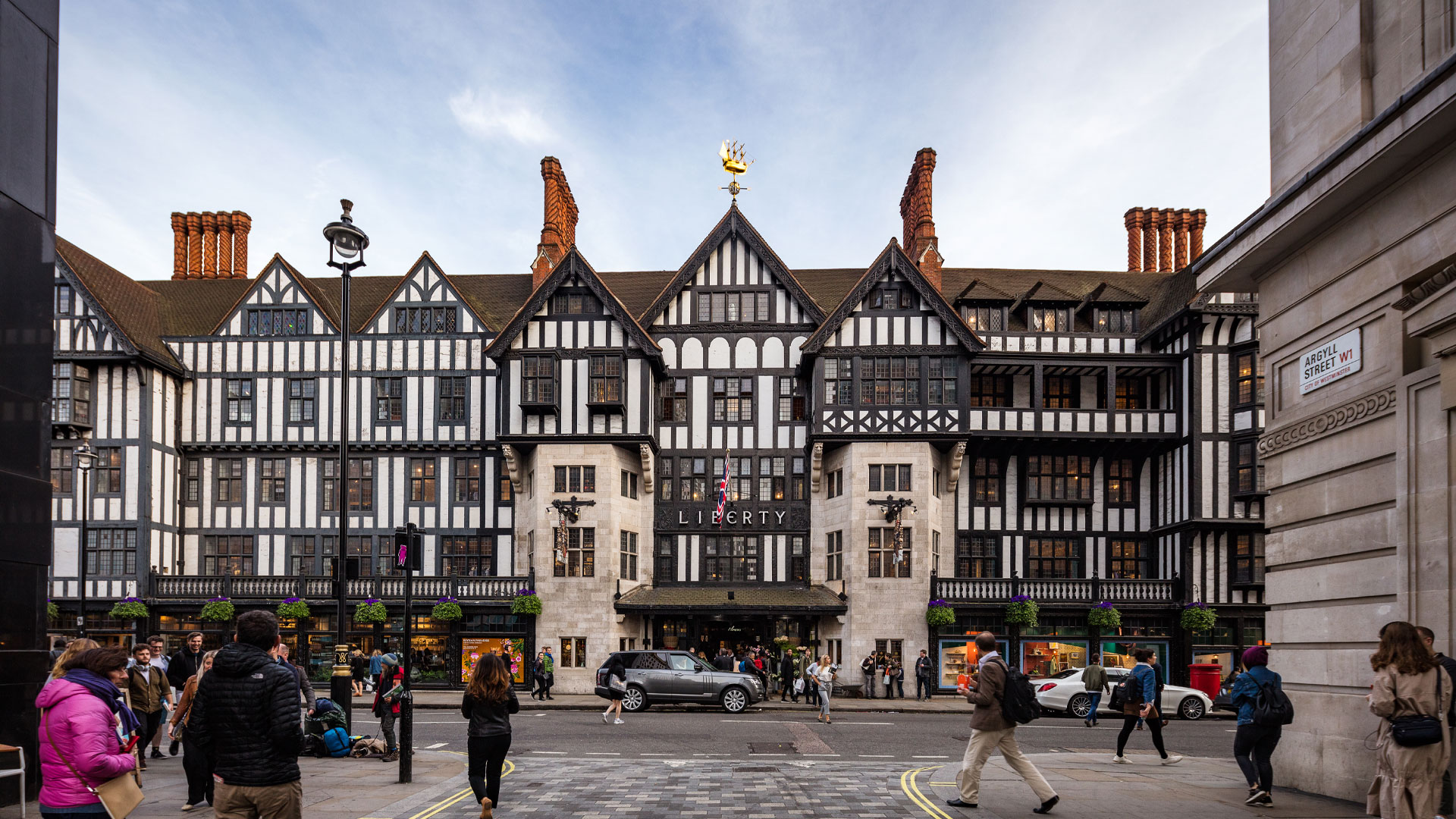 The outside and main entrance to Liberty taken from across the road in Argyll Street with cars and people passing by.
