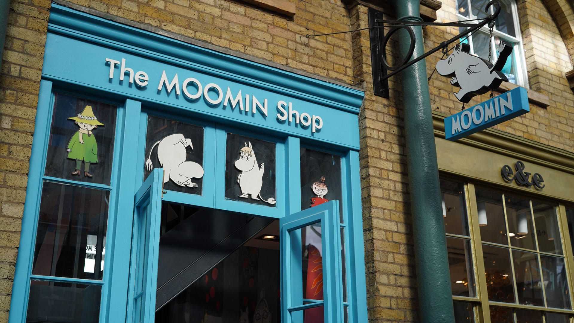 The blue-painted shop entrance which features drawings of Moomin characters in the upper windows.