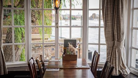 A table in the window with a view of the river. Image courtesy of Greene King.