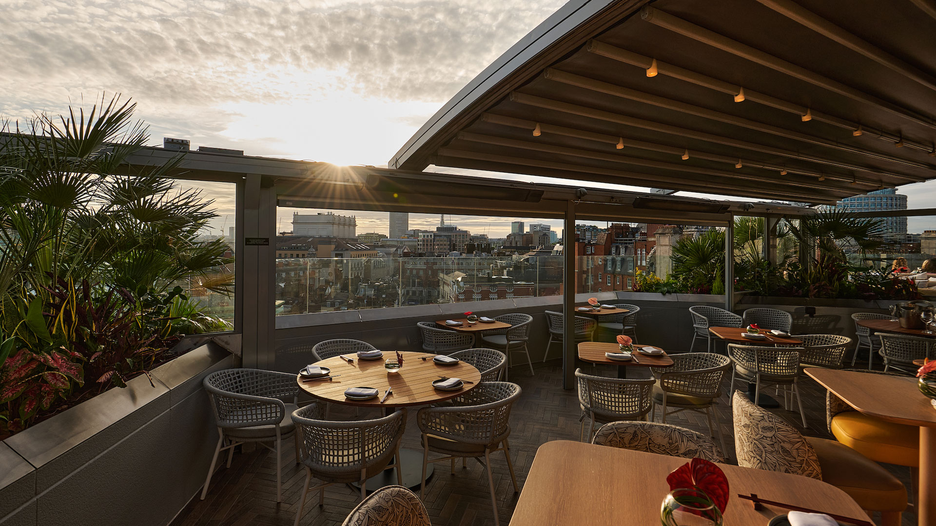 Tables and chairs on the terrace with a partially open roof above.
