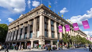 A corner view of the outside of Selfridges department store on a sunny day.