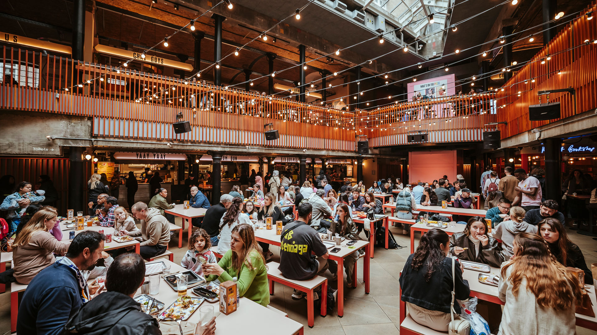 People sat eating and drinking at tables inside Seven Dials Market.