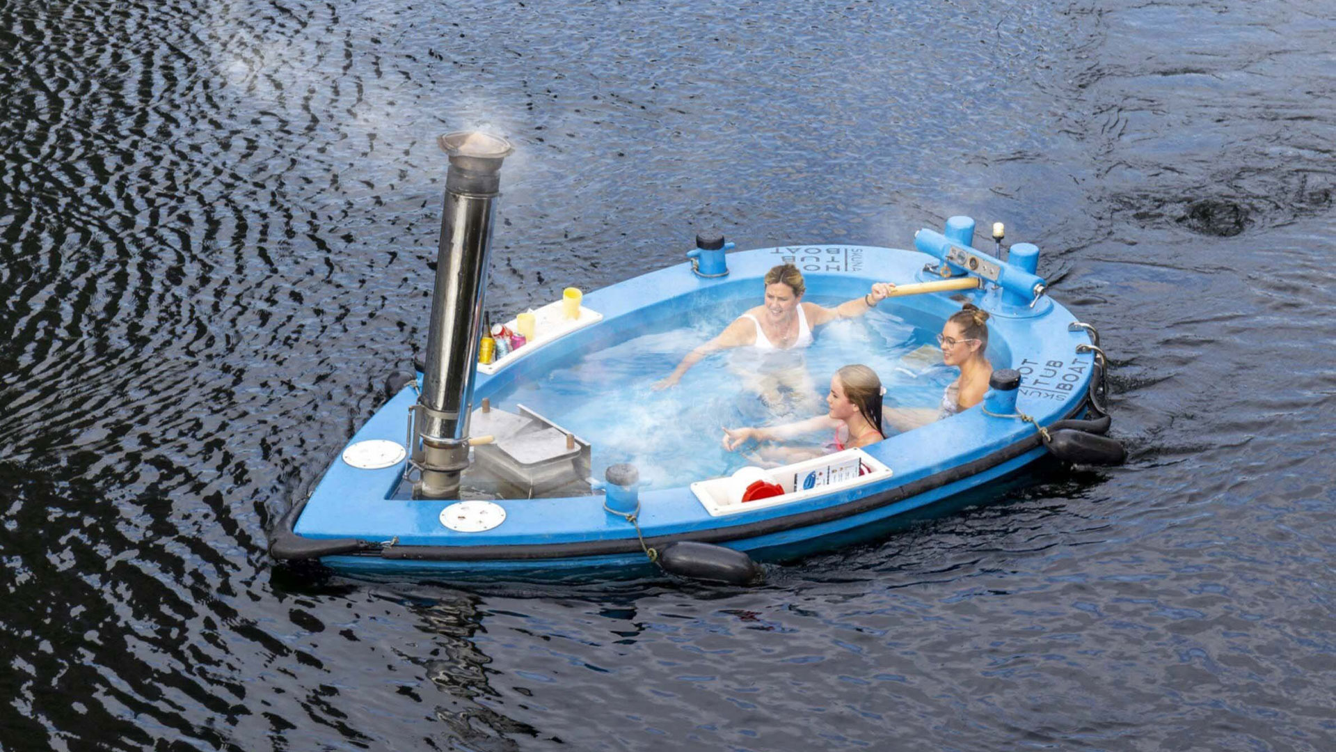 Hop in the hot rub Skuna Boat and unwind on the water. Credit: Skuna Boats. Image courtesy of Skuna Boats. Three people relax in a boat-shaped hot tub floating on the river.