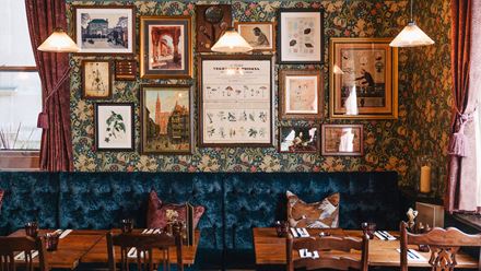 A wall full of pictures above tables and chairs. Image courtesy of Greene King.
