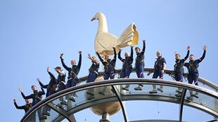A glass platform high up in the air, with people in blue jumpsuits with their hands in the air