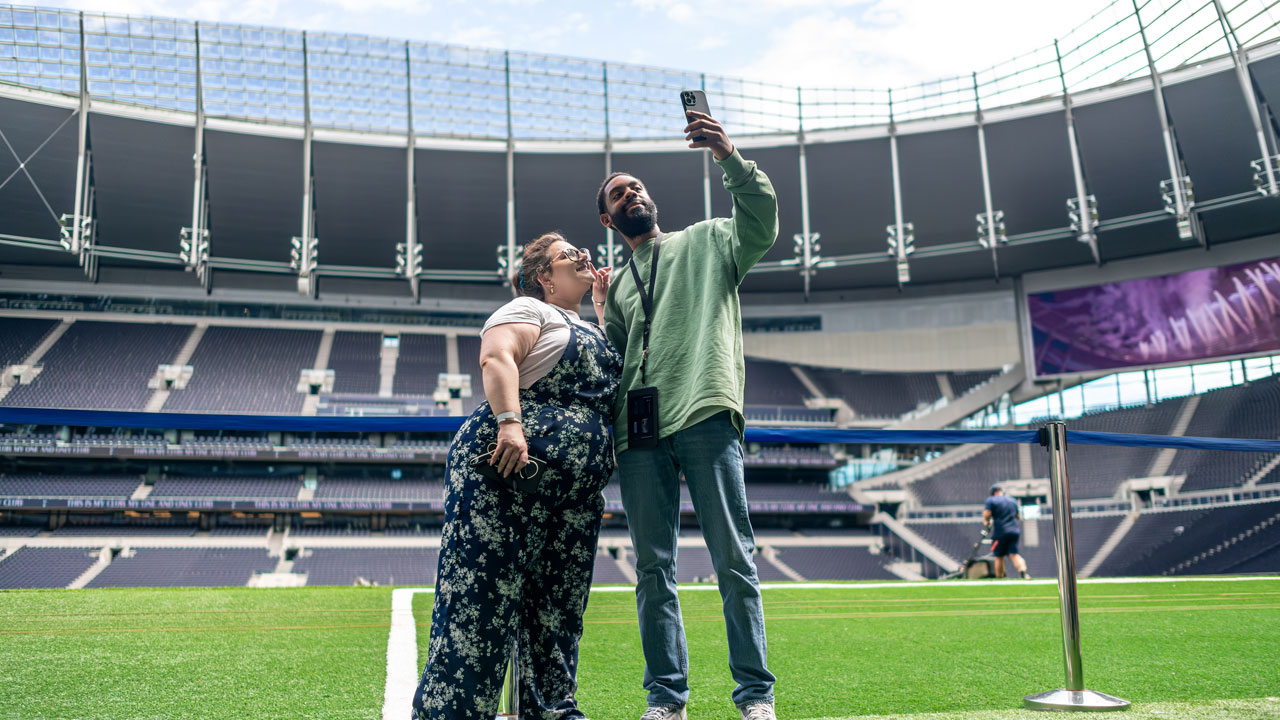 Vivez une expérience comme nulle autre pareille et marchez dans les pas de vos joueurs préférés en visitant le stade de Tottenham Hotspur. © visitlondon.com/Michael Barrow Un homme et une femme prennent un selfie ensemble à l'intérieur du stade de tottenham Hotspur à Londres.