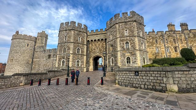The large beige stone walls of windsor castle under a blue sky.