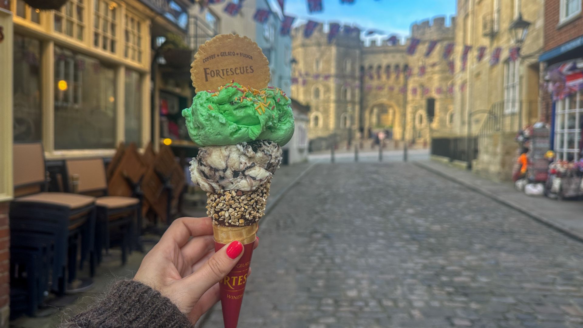 A hand holds an ice cream cone with a scoop of oreo and green mint choc chip.